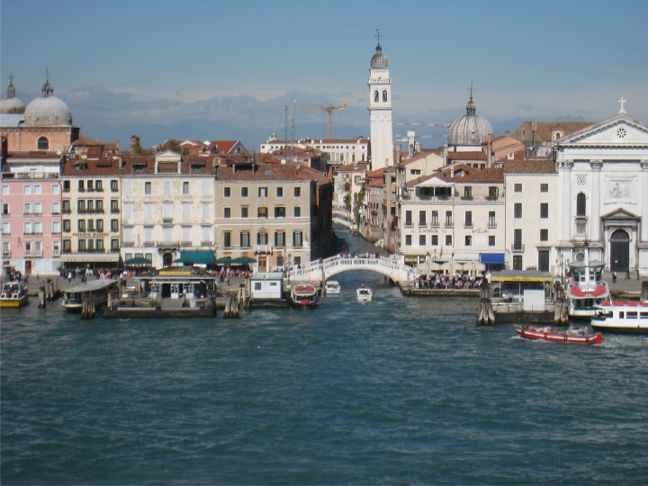 A Venetian canal and pedestrian bridge, seen from the height of the cruise ship.