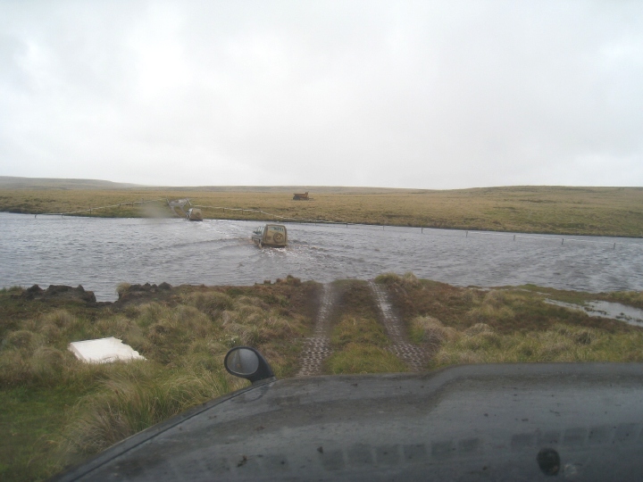 Vehicles are seen driving through deep water, the car from which the photo is taken is about to follow the same path.