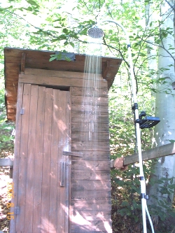 an outhouse, with a running shower in front of it