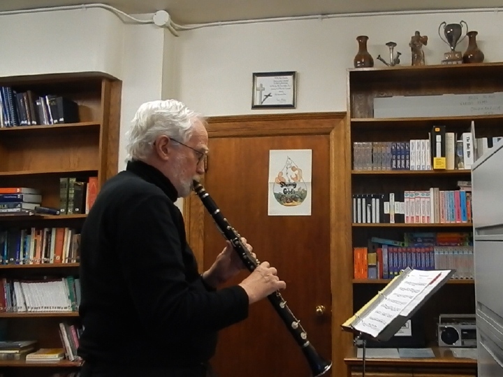 Tony, in profile, playing the clarinet in a library
