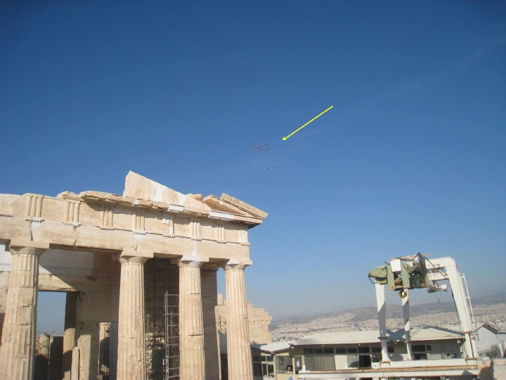Military jets circle the Acropolis. This is a still image, and the jets are hardly visible, so there is a graphic arrow to indicate their location