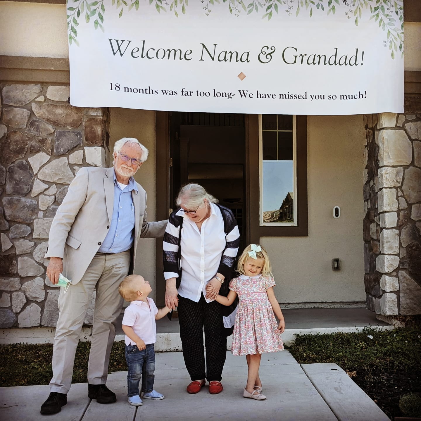 Tony and Heather, with grandchildren, under a large welcome sign